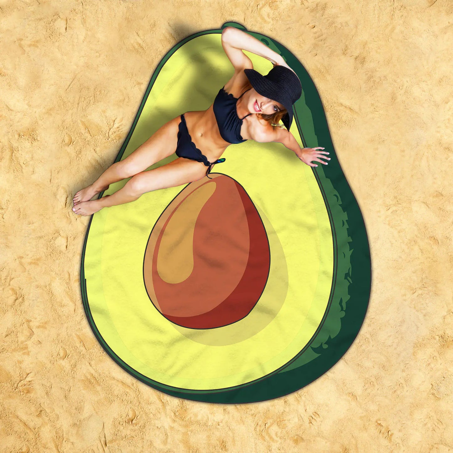 Person lying on an avocado-shaped beach mat on a sandy background